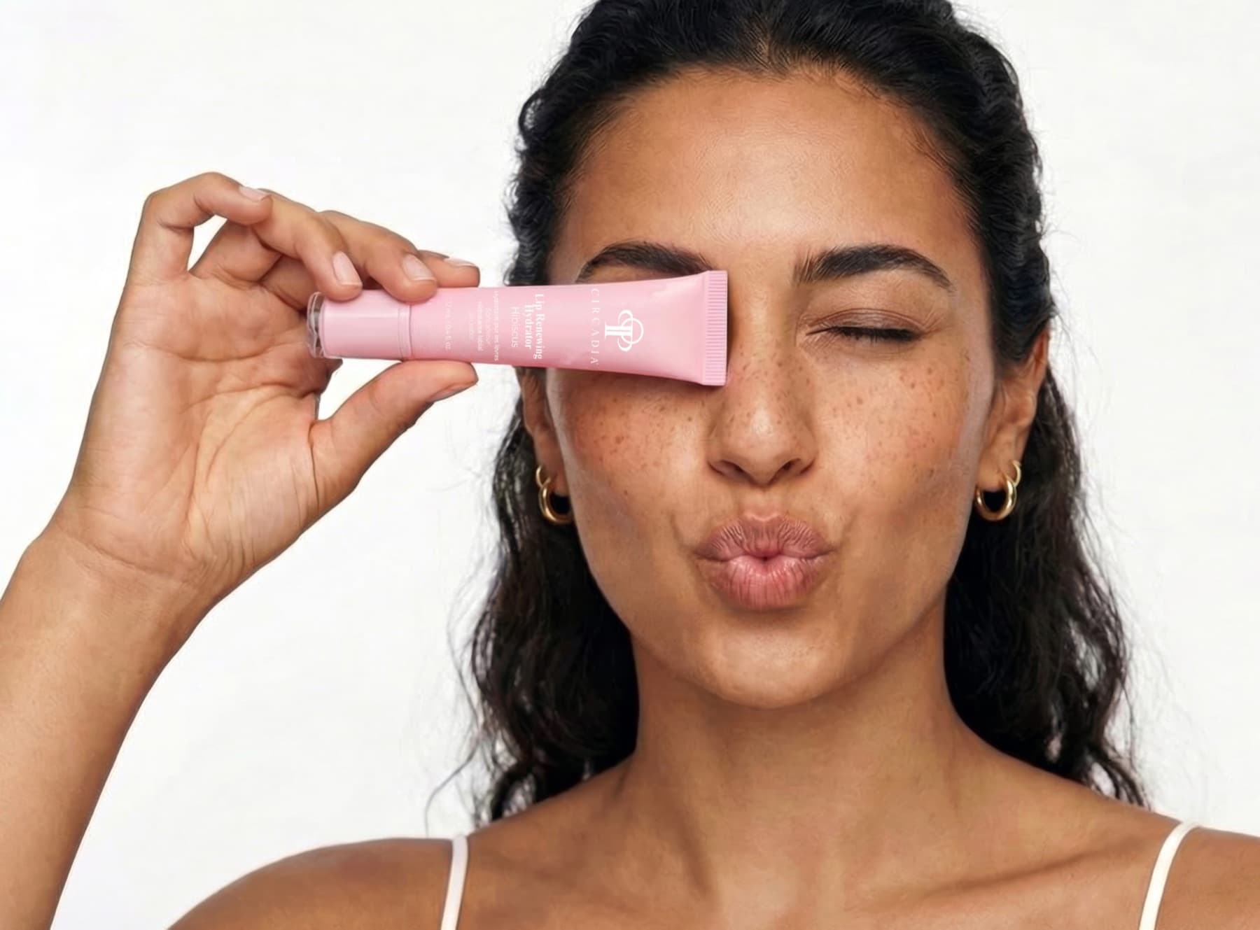 Woman holding a Circadia Lip Renewing Hydrator in Hibiscus